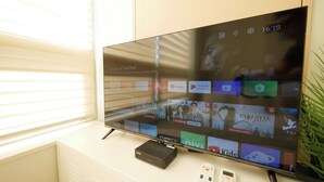 A flat-screen TV mounted on a wall with a D-Link DMR-1250N network attached to it.