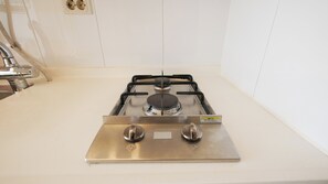 Une cuisine équipée d’une cuisinière à gaz en acier inoxydable, d’un évier et d’un robinet.
