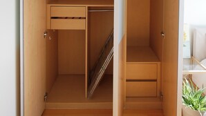 A walk-in closet with open doors, wooden shelving, and a hanging rod.