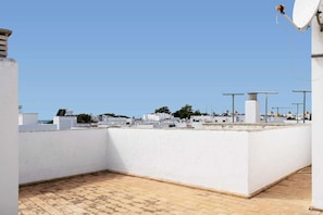 En takterrass med fri utsikt över stadsbilden, vita väggar och ett klinkergolv.
