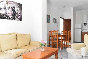 Ein Wohnzimmer mit einer Couch, einem Holztisch und einem Essbereich mit Tisch und Stühlen.