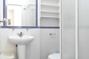 Ein Badezimmer mit einem weißen Waschbecken, einer Toilette und einer Duschkabine.