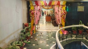 A hotel lobby with a floral archway, potted plants, and a staircase. - Hotel Windsor (Patna)