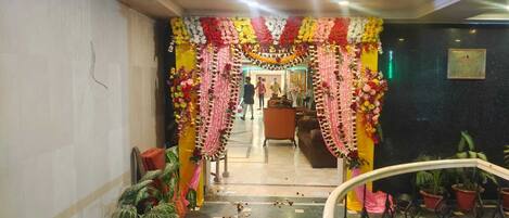 A hotel lobby with a floral archway, potted plants, and a staircase.