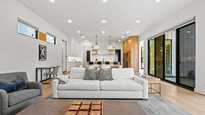 A modern living room with a sofa, coffee table, and artwork on the walls. - Stunning Modern Farmhouse w/ Pool (Dallas)