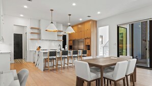 A modern kitchen with wooden cabinets, a central island, and pendant lighting. - Stunning Modern Farmhouse w/ Pool (Dallas)