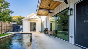 A modern house with a swimming pool, outdoor seating, and a large sliding glass door. - Stunning Modern Farmhouse w/ Pool (Dallas)