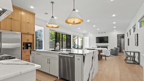 A modern kitchen with a central island, stainless steel appliances, and pendant lighting. - Stunning Modern Farmhouse w/ Pool (Dallas)