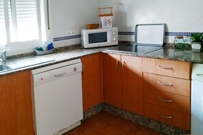 A kitchen with a dishwasher, microwave, toaster, and granite countertop. - Chalet Chaparrillo Conil Rentals with Private Pool (Cádiz)