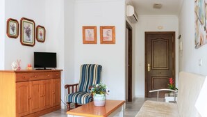 A living room with a wooden cabinet, a striped armchair, a white table, and a sofa.