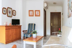 Een woonkamer met een houten kast, een gestreept fauteuil, een witte tafel en een bank.
