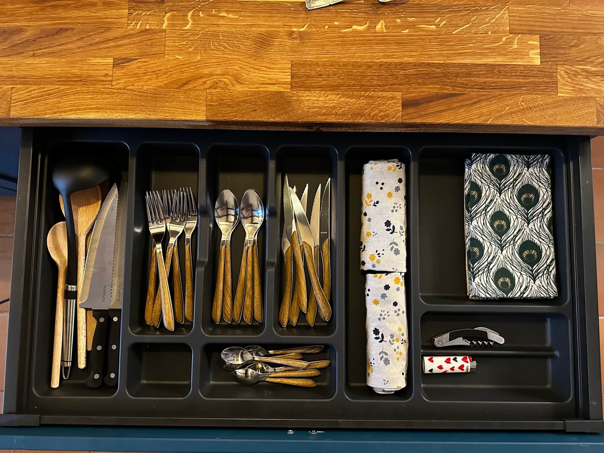 A drawer with various kitchen utensils and a napkin holder.