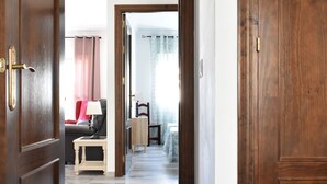 Una porta de fusta que dona a un espai amb un sofà, una taula petita i una cadira.