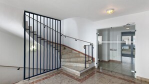 A staircase with a metal railing, a tiled floor, and a glass door leading to another room. - Studio Emma – Sea View with Terrace (Le Croisic)