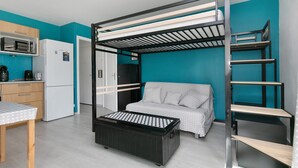 A compact room with a bunk bed, kitchenette, and a small table. - Studio Emma – Sea View with Terrace (Le Croisic)