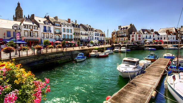 A harbor with boats docked, a bridge, and buildings with balconies. - Studio Emma – Sea View with Terrace (Le Croisic)