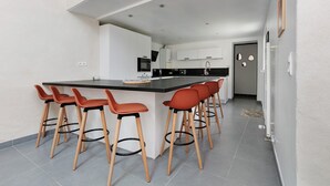 Une cuisine moderne dotée d’un îlot central, de tabourets de bar et d’un coin repas.