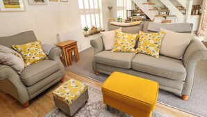 Un salón con un sofá, un reposapiés y una escalera.