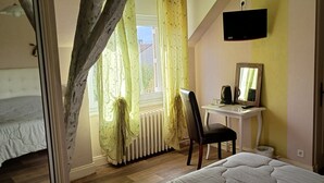 Une chambre à coucher comprenant un lit, un bureau, une chaise, un radiateur et un téléviseur fixé au mur.