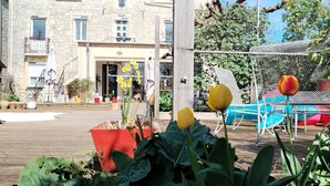 Une cour dotée d’une terrasse en bois, de plantes en pot et d’un bâtiment à la façade en pierre.
