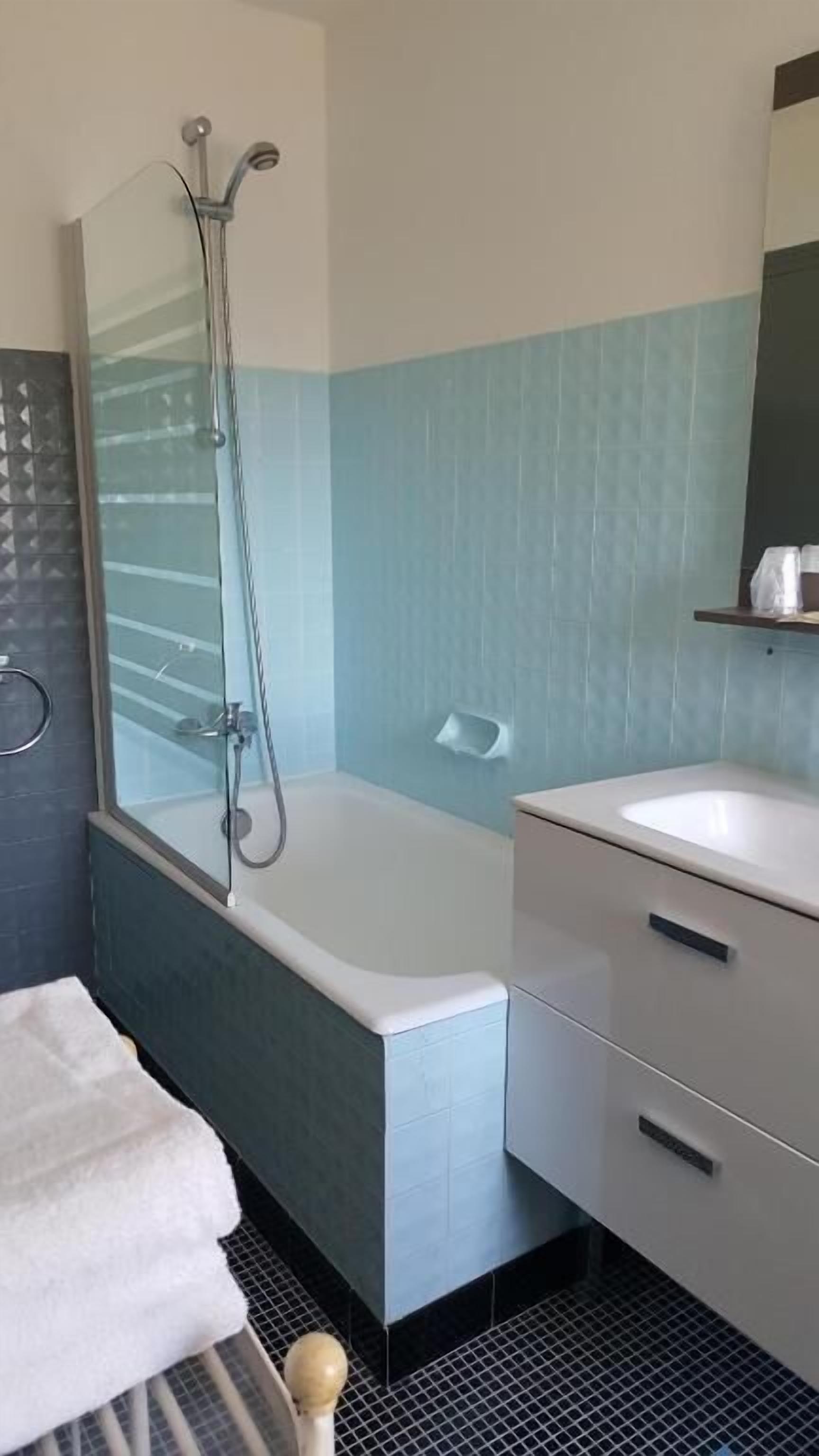 Ein Badezimmer mit einer Badewanne, einer Dusche, einem Waschbecken und einem Spiegel.