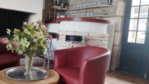 Une pièce chaleureuse avec une cheminée, des fauteuils rouges et un vase de fleurs posé sur une table en bois.