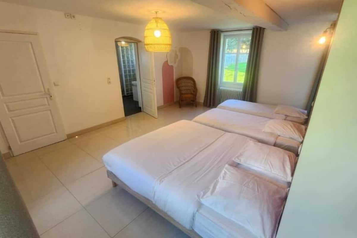Un dormitorio con dos camas, una puerta, una silla y una ventana.
