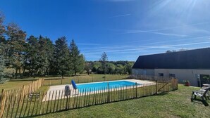 A swimming pool surrounded by a wooden fence, with a grassy yard and trees in the background. - Chambres Domaine de Saint Marc (Saint-Médard)