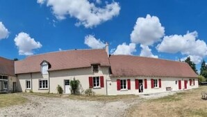 A two-story building with a red-tiled roof, a small porch, and a gravel driveway. - Chambres Domaine de Saint Marc (Saint-Médard)