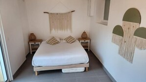 A bedroom with a bed, two bedside tables, a hanging macrame wall decoration, and a window. - Chambres Domaine de Saint Marc (Saint-Médard)