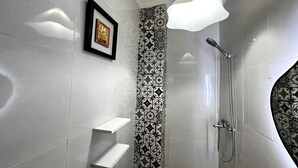 Ein modernes Badezimmer mit Dusche, einem gerahmten Bild an der Wand und gemusterten Fliesen.