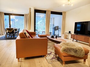 Ein modernes Wohnzimmer mit einer Couch, einem Hocker und einem Flachbildfernseher.