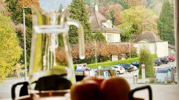 A view of a mountain landscape through a window, with a pitcher and glasses on a table in the foreground.