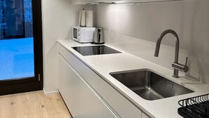 Ett modernt kök med en inbyggd mikrovågsugn, en diskho i rostfritt stål och en svart kaffemaskin.