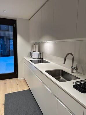 A modern kitchen with a built-in microwave, a stainless steel sink, and a black coffee machine.