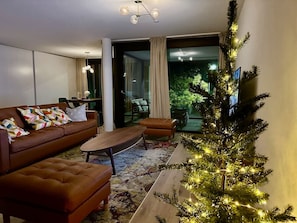 A modern living room with a brown leather sofa, a wooden coffee table, and a Christmas tree with lights. - Modern Apartment • Balcony • AC • Interlaken West (Interlaken)