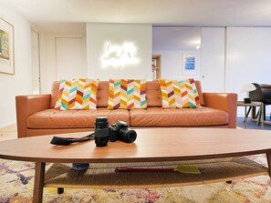 A living room with a sofa, two cameras, and a coffee table.