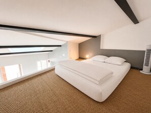A modern bedroom with a bed, a standing heater, and a view through a skylight. - 40 m² apartment facing the Old Port of La Rochelle (La Rochelle)