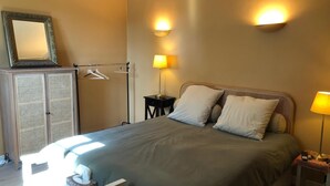 Ein ordentlich eingerichtetes Hotelzimmer mit Bett, Nachttischlampen, einem Kleiderschrank und einem Spiegel.
