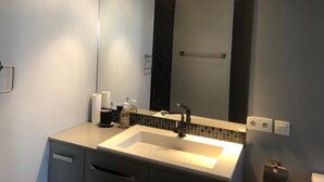 Ein modernes Badezimmer mit großem Spiegel, Waschbecken und Handtuchhalter.