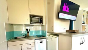 Cuina compacta amb microones, rentaplats i un televisor de pantalla plana penjat sobre la barra.