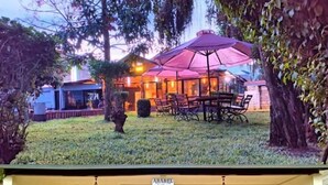 A hotel with a covered outdoor seating area, a front porch with chairs, and a well-maintained garden. - Riverside Villas Nanyuki (Nanyuki)