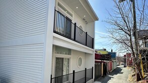 A two-story building with a balcony, a garage door, and a driveway. - Lime Suite at Jellybean House (St. John's)