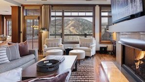 Una sala moderna con chimenea, ventanas amplias con vistas a la montaña y asientos cómodos.