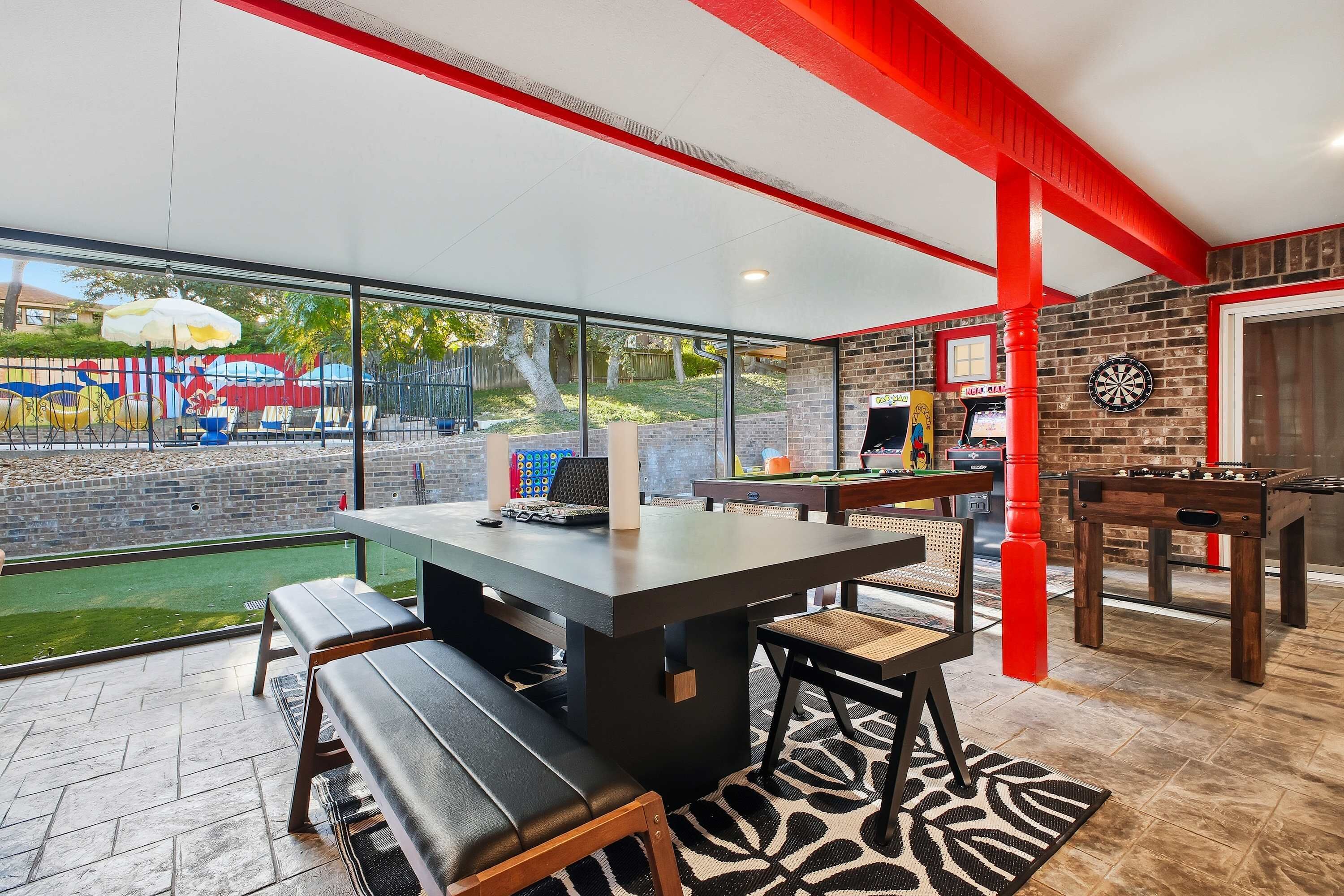 A modern indoor space with a large table, seating, and a dartboard.