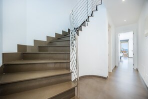 Una escalera moderna con barandilla de metal que conduce a un pasillo luminoso.