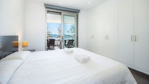 A modern hotel room with a large bed, a sliding glass door to a balcony, and a wardrobe. - Apartment 'Voramar 33A Joana Duplex' with Sea View, Private Terrace and Wi-Fi (Port Pollensa)