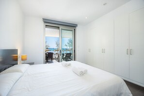 Habitación de hotel moderna con una cama grande, una puerta corredera de vidrio a un balcón y un armario.
