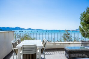 Um terraço com mesa e cadeiras, com vista para um corpo de água e barcos.