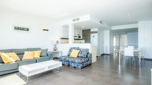 A modern living room with a sofa, a coffee table, and a dining area with chairs. - Apartment 'Voramar 33A Joana Duplex' with Sea View, Private Terrace and Wi-Fi (Port Pollensa)